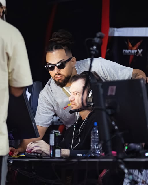 vinAo de óculos escuros, debruçado sobre a mesa, ajustando a máquina de um jogador na Circuit X